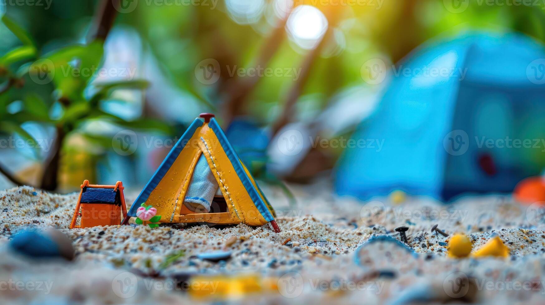 Colorful miniature tents set in sandy terrain, surrounded by greenery and blurred camping scene photo