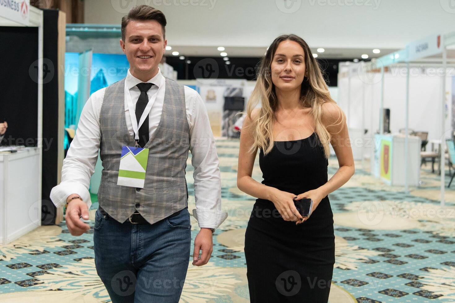 A business couple walking through a trade show, engaging with new ideas and insights to drive their professional growth photo