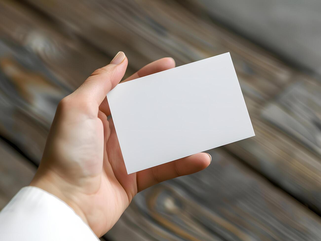 A person holding a blank business card on a wooden table photo
