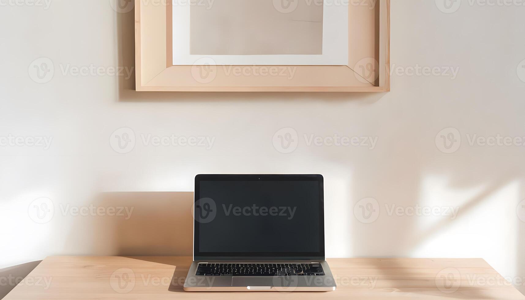 A laptop sits on a wooden desk next to a framed picture photo