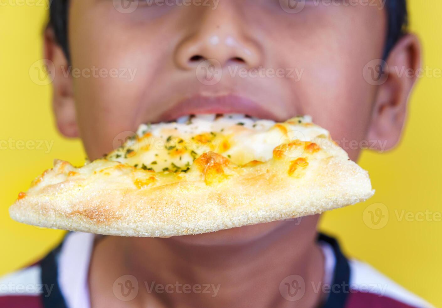 Close up of cheerful boy with a slice of pizza in his mouth photo