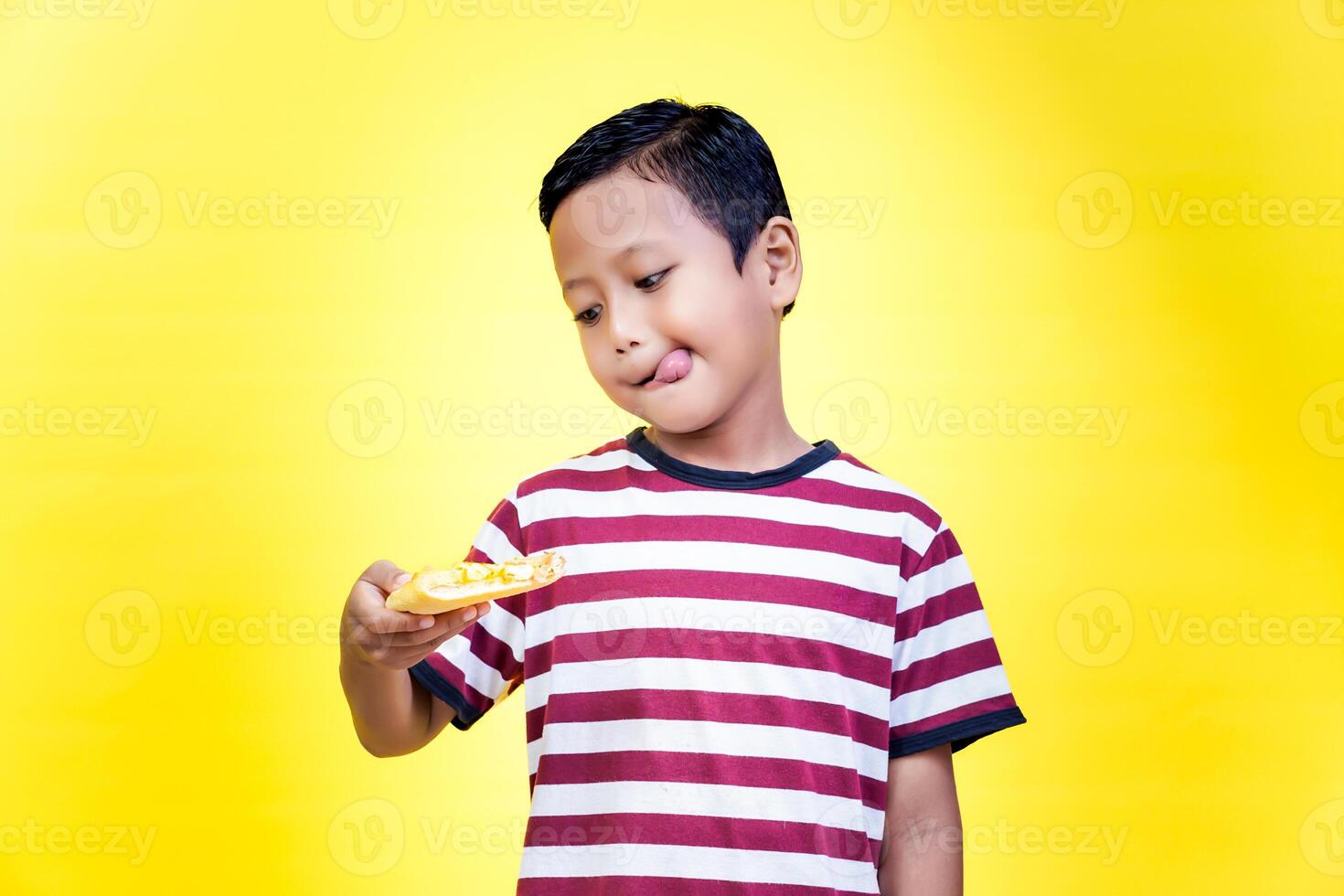 excited asian young boy holding a piece of pizza photo
