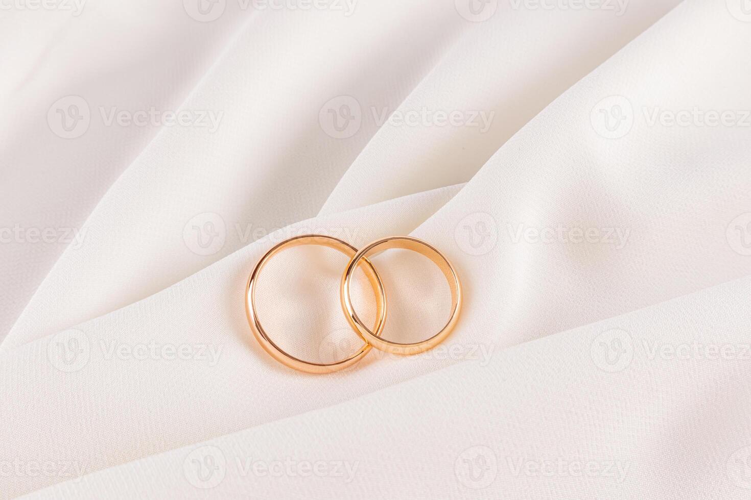 Two gold wedding rings lie on soft folds of elegant silk fabric. Beautiful wedding design layout. A copy of the space. wedding background. photo