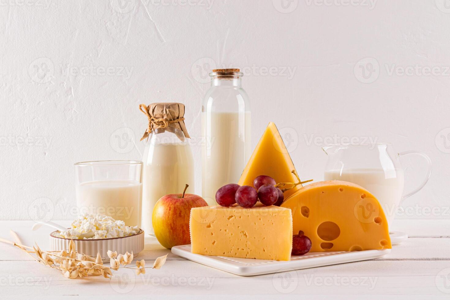 Different varieties of cheese, bottles, glass, jug of milk on a white background. Traditional products of the Shavuot holiday. Front view. photo