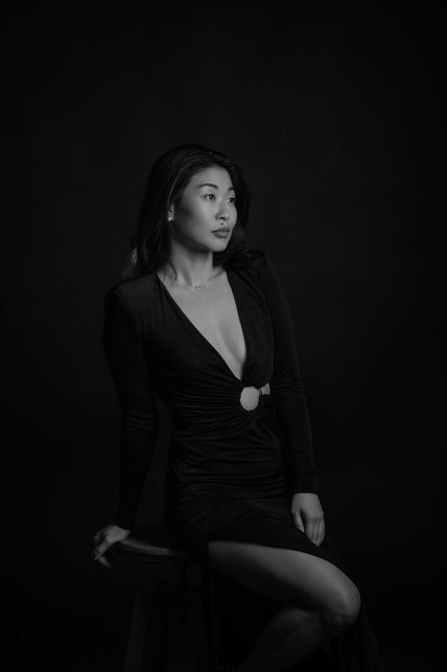 The contrast between the black dress and the dark studio background creates a powerful and sophisticated look. photo