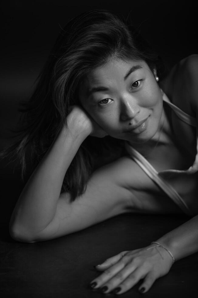An Asian woman poses for a studio portrait, her face illuminated by balanced lighting that enhances her delicate features. photo