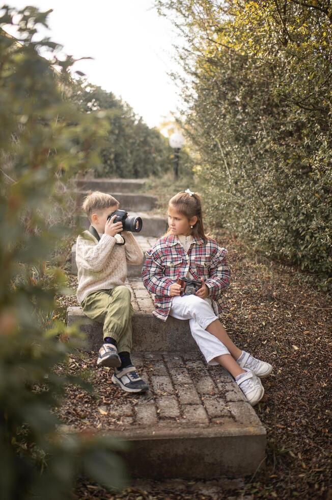 The boy and girl sit on the worn steps, cameras in hand, their eyes filled with curiosity as they frame the world through their lenses. photo
