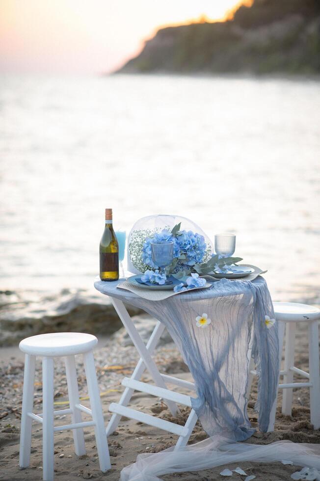 The sky and sea blend in deep blue tones as a romantic dinner unfolds, the clink of wine glasses echoing softly in the evening breeze. photo