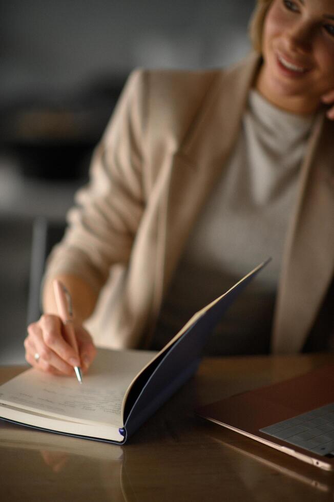 She leans slightly forward, engaged in her work, alternating between her laptop and handwritten notes. photo