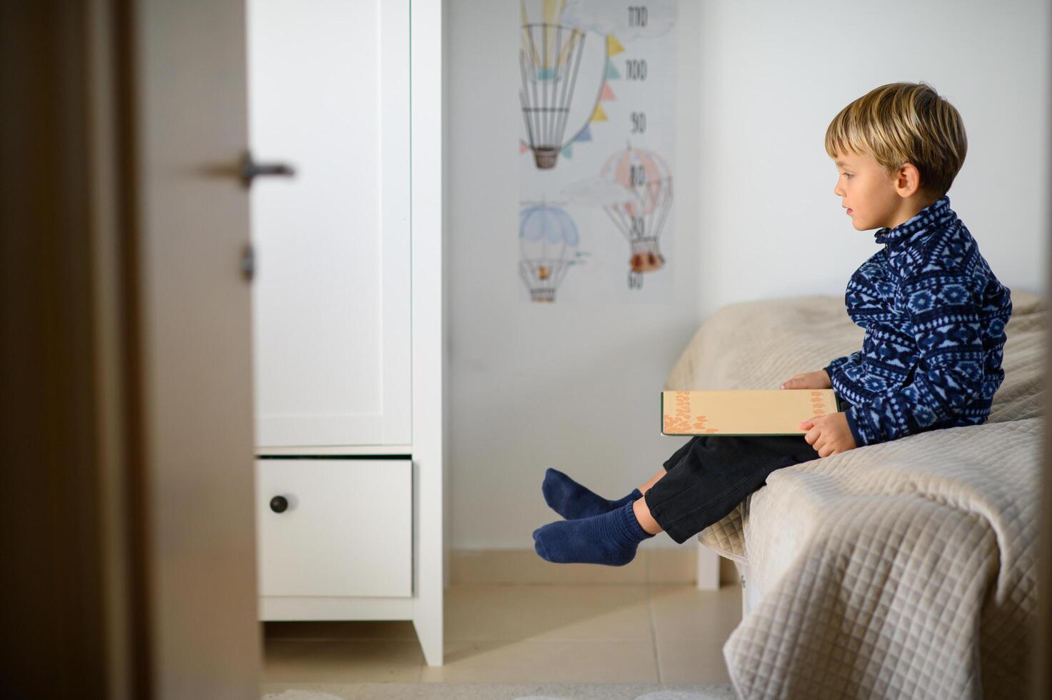 A child sits in a bright and cozy nursery, flipping through the pages of a book. Focused and curious, they explore the story with wide eyes. photo