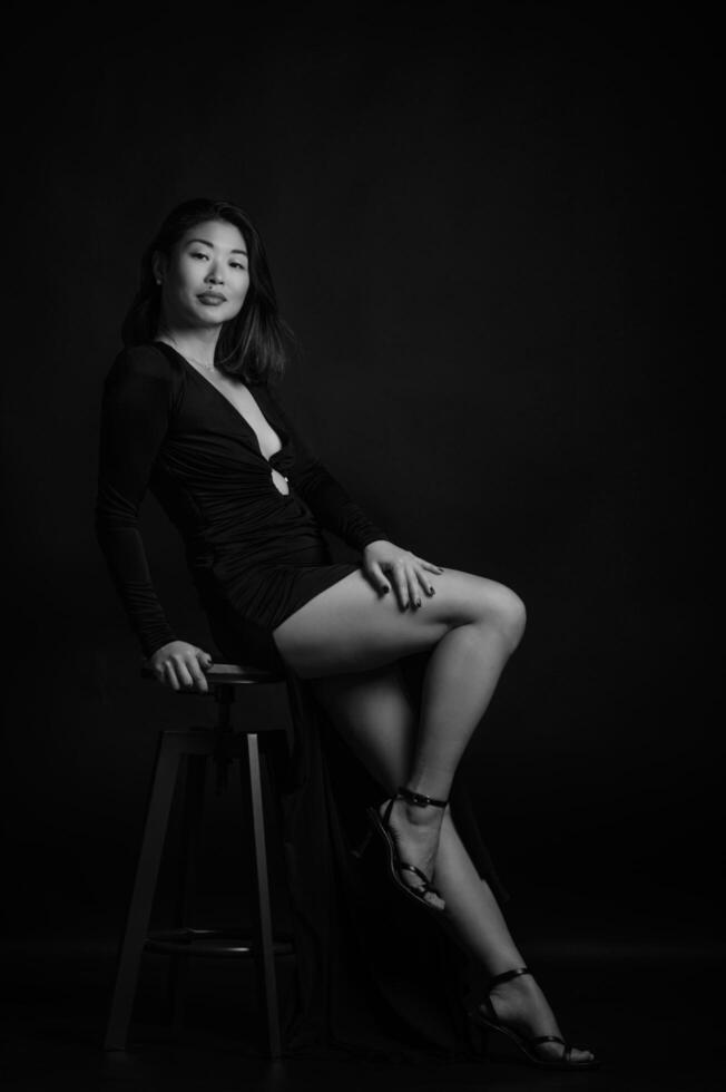 A serene portrait of an Asian woman in a black dress, the dark backdrop emphasizing her graceful expression photo