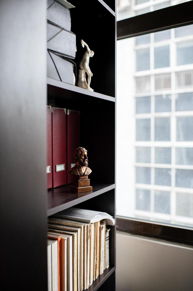 A well organized office space features shelves of documents alongside a thoughtful Aristotle bust. photo