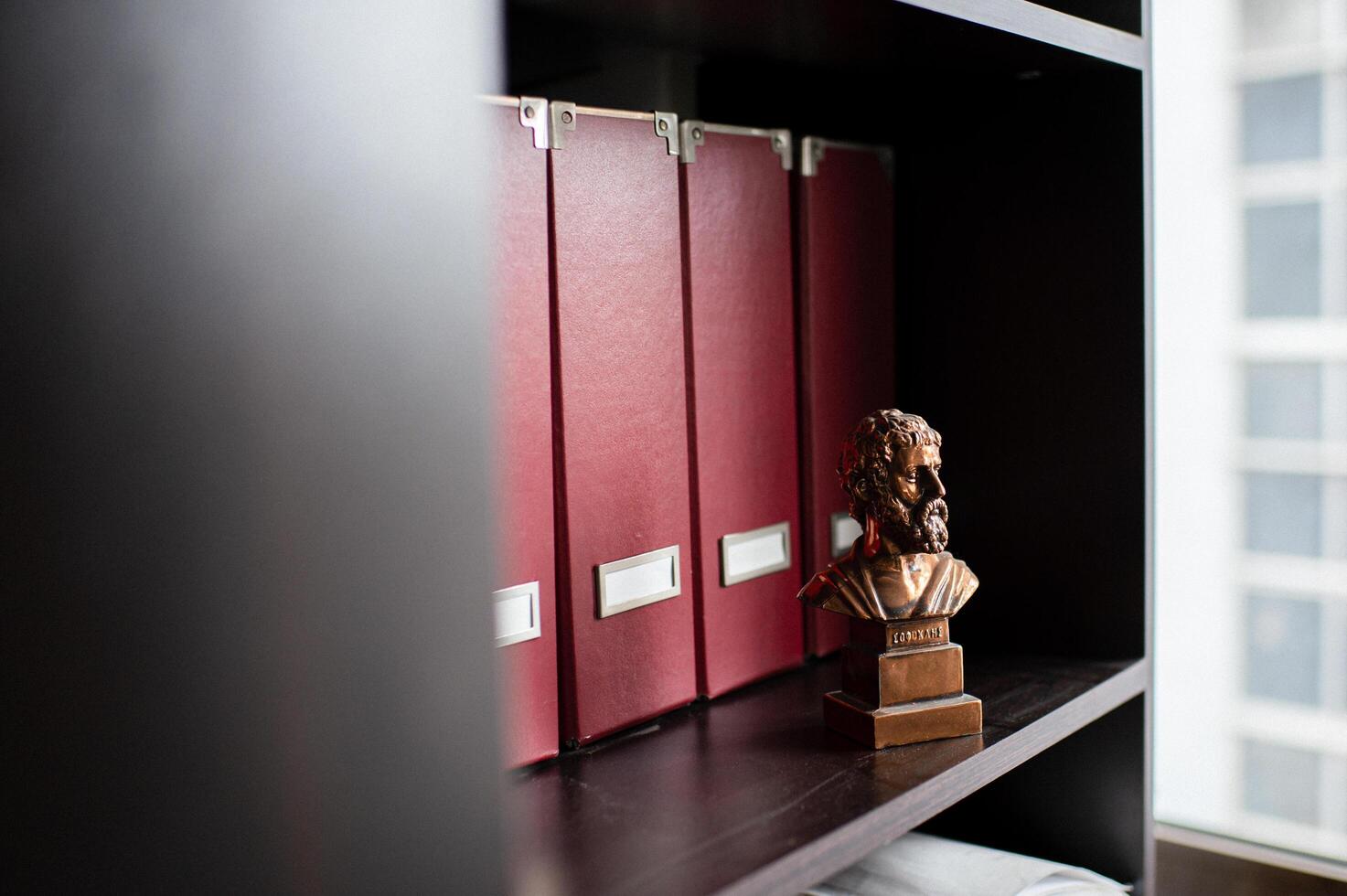 The contrast of modern office folders and an ancient Aristotle statue creates a unique atmosphere. photo