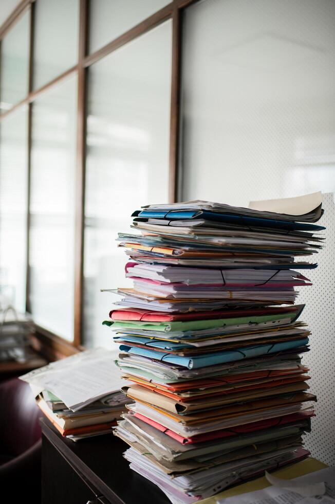 An office filled with stacks of document folders, creating a busy and organized workspace. photo