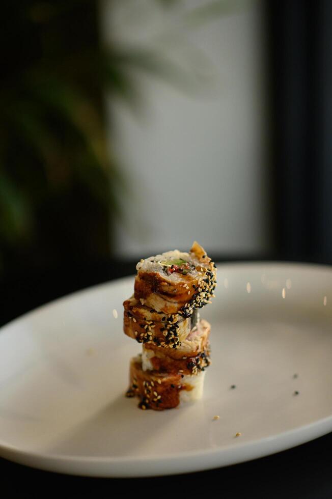 A beautifully plated eel sushi rests on a sleek dish, its glossy unagi sauce adding a rich, savory sheen to the tender fish. photo