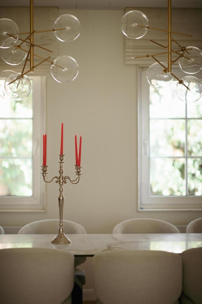 A candle holder with glowing candles sits on the table beneath elegant chandeliers, casting a warm and cozy ambiance. photo