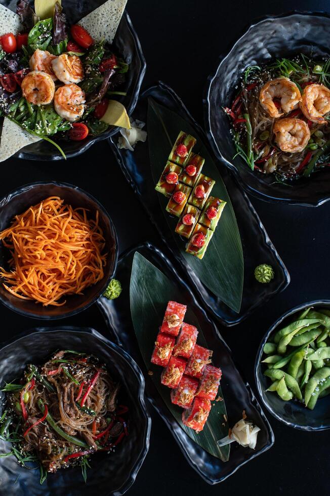 A beautifully arranged sushi set sits on sleek black plates, surrounded by elegant chopsticks and dipping sauces, ready to be enjoyed. photo