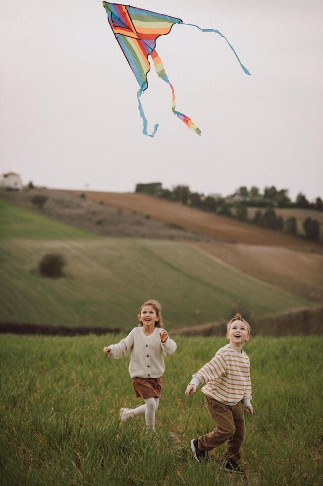 Carefree and laughing, Childs run through the meadow, their kite soaring like a bird. photo