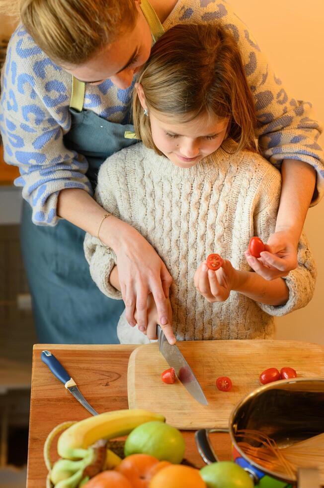 The child looks intently at the cutting board, trying not to get her hands messy with the juicy tomatoes. photo