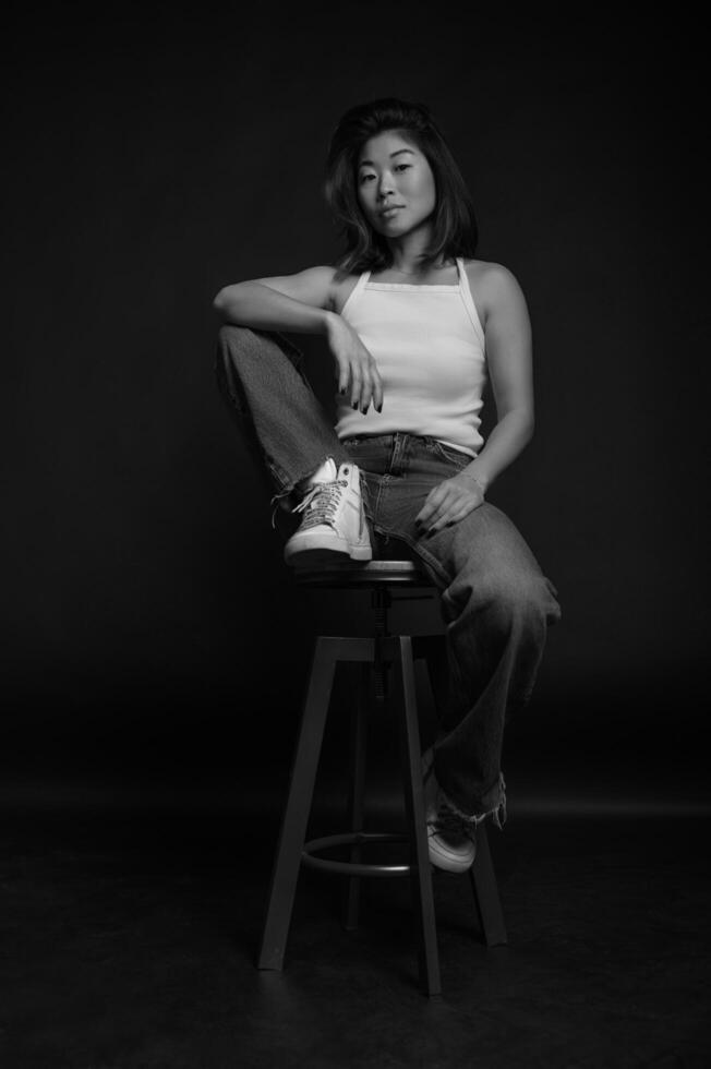 A striking portrait of an Asian woman in the studio, her confident expression framed by dramatic lighting. photo
