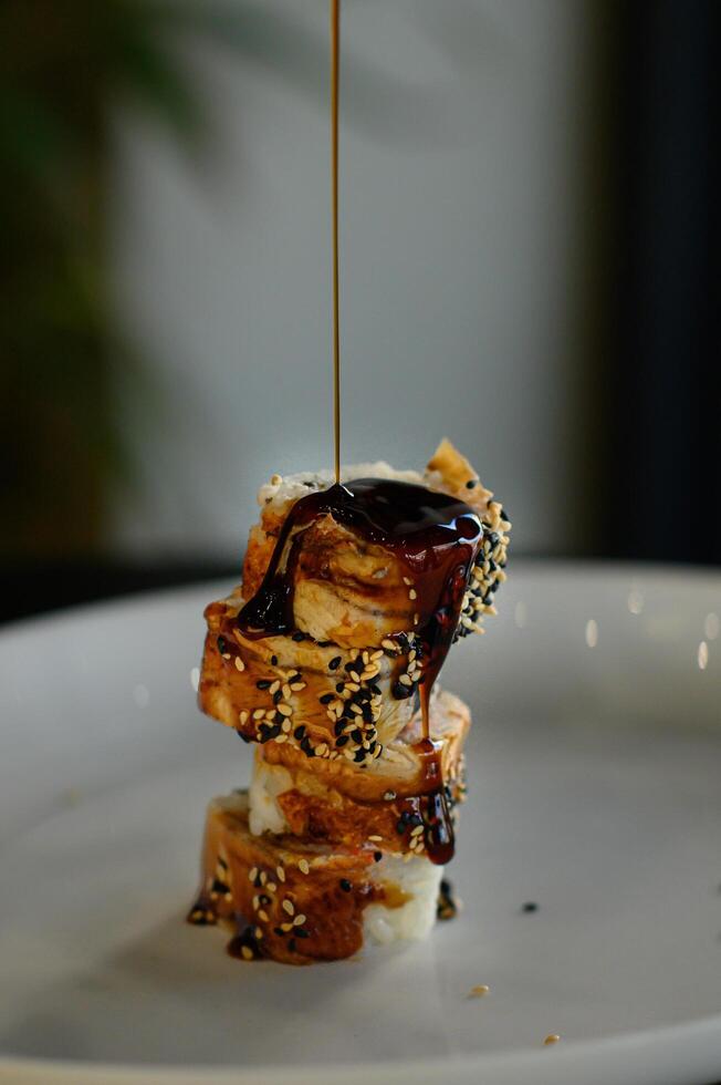 A smooth stream of unagi sauce cascades over the sushi, coating the delicate eel in a glossy, savory-sweet glaze. photo