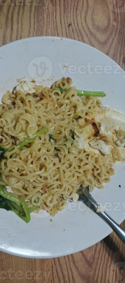 Instant noodles with vegetables and egg.A plate of instant noodles mixed with vegetables and egg, offering a simple and delicious homemade meal. photo