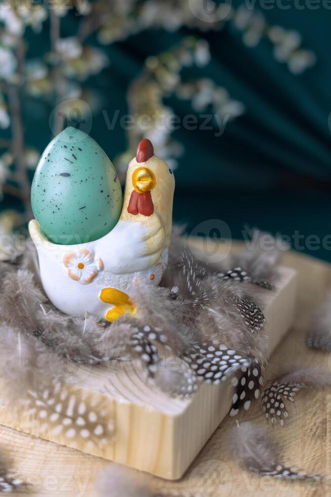 Easter chicken stand with egg on a wooden background with feathers. photo