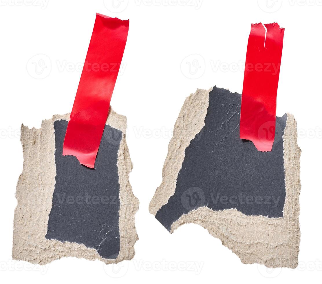 Torn piece of black cardboard attached to red piece of electrical tape, isolated background. photo