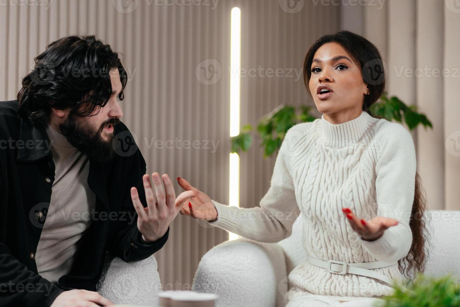 African woman talks to boyfriend about relationship problem on counseling session or couples therapy. Annoyed American man sitting on chair and listening his girlfriend photo