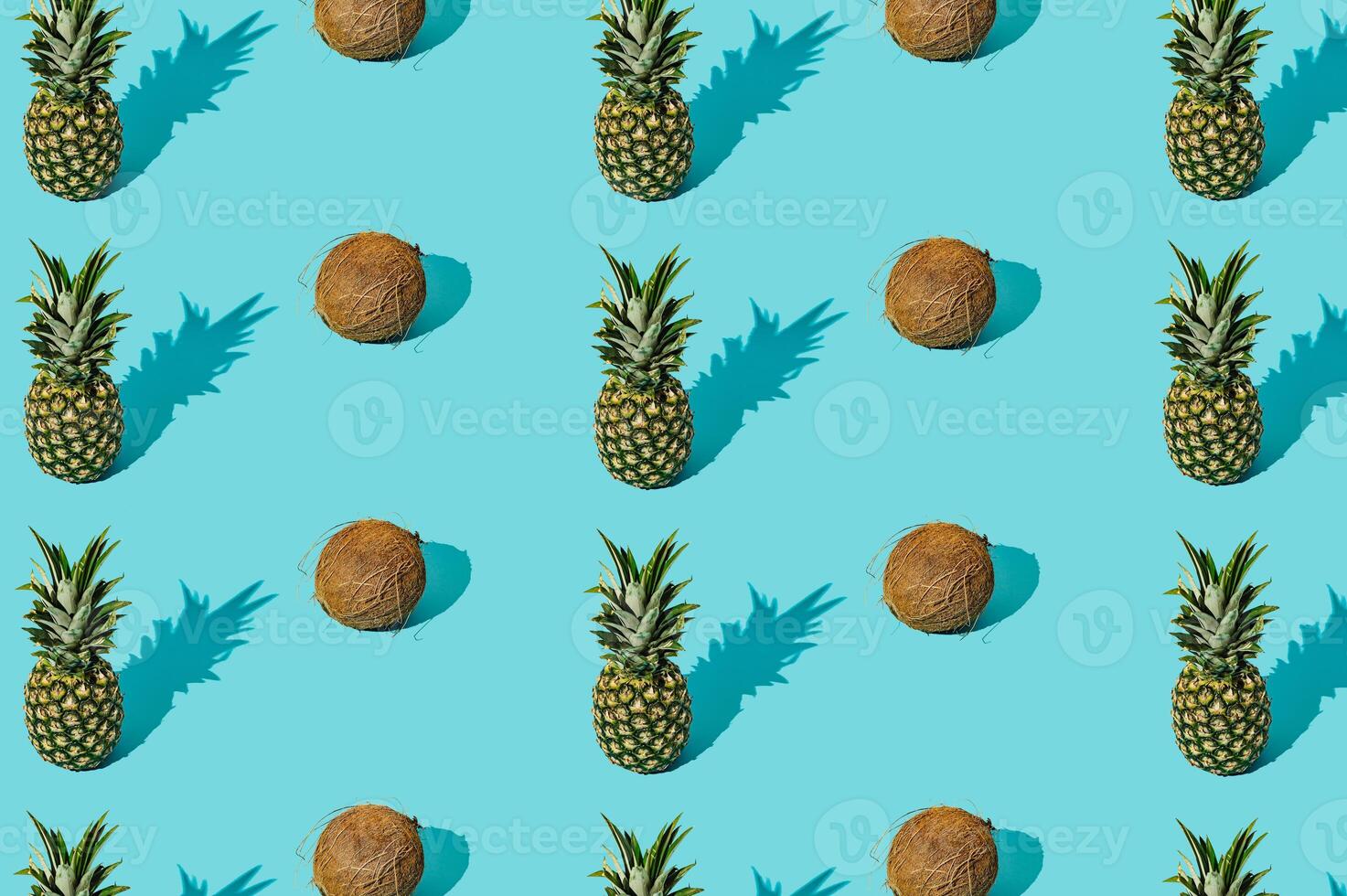 Trendy sunlight summer fruit pattern made of coconuts and pineapples on light blue background. Nature summer concept. Summer fruit aesthetic. photo