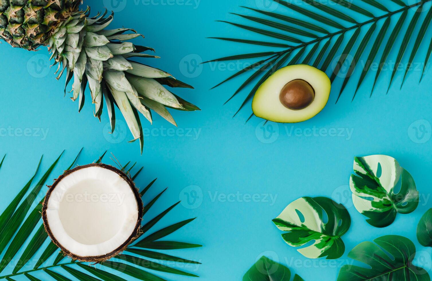 Creative layout made with pineapple, coconut, avocado and green tropical leaves with on light blue background. Summer tropical fruits and leaves idea. Minimal food concept. Exotic flat lay, top view. photo