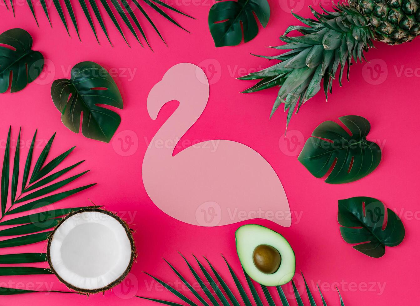 Creative layout with pineapple, coconut, avocado and tropical leaves with pink flamingo paper card note copy space on pink background. Summer tropical fruits and leaves idea. Food concept. Flat lay. photo