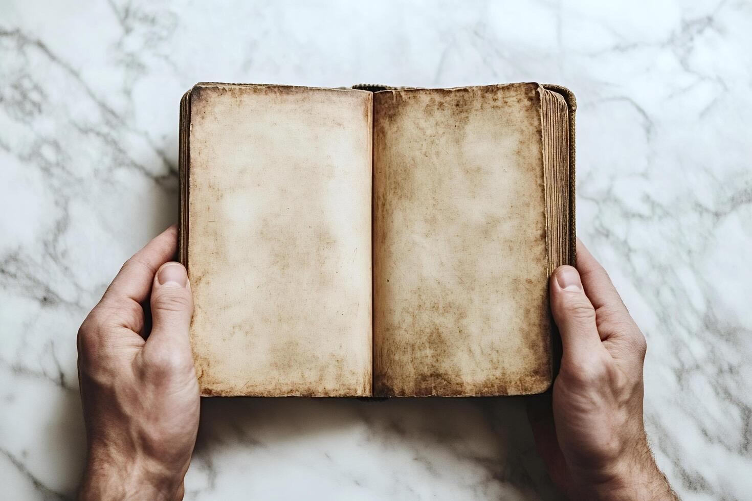Hands holding an old blank book on marble surface photo