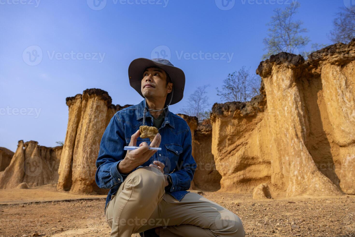 Asian geologist is exploring and surveying the sample rock on the natural sandstone canyon resource site for scientific research and archeology for understanding mother earth photo
