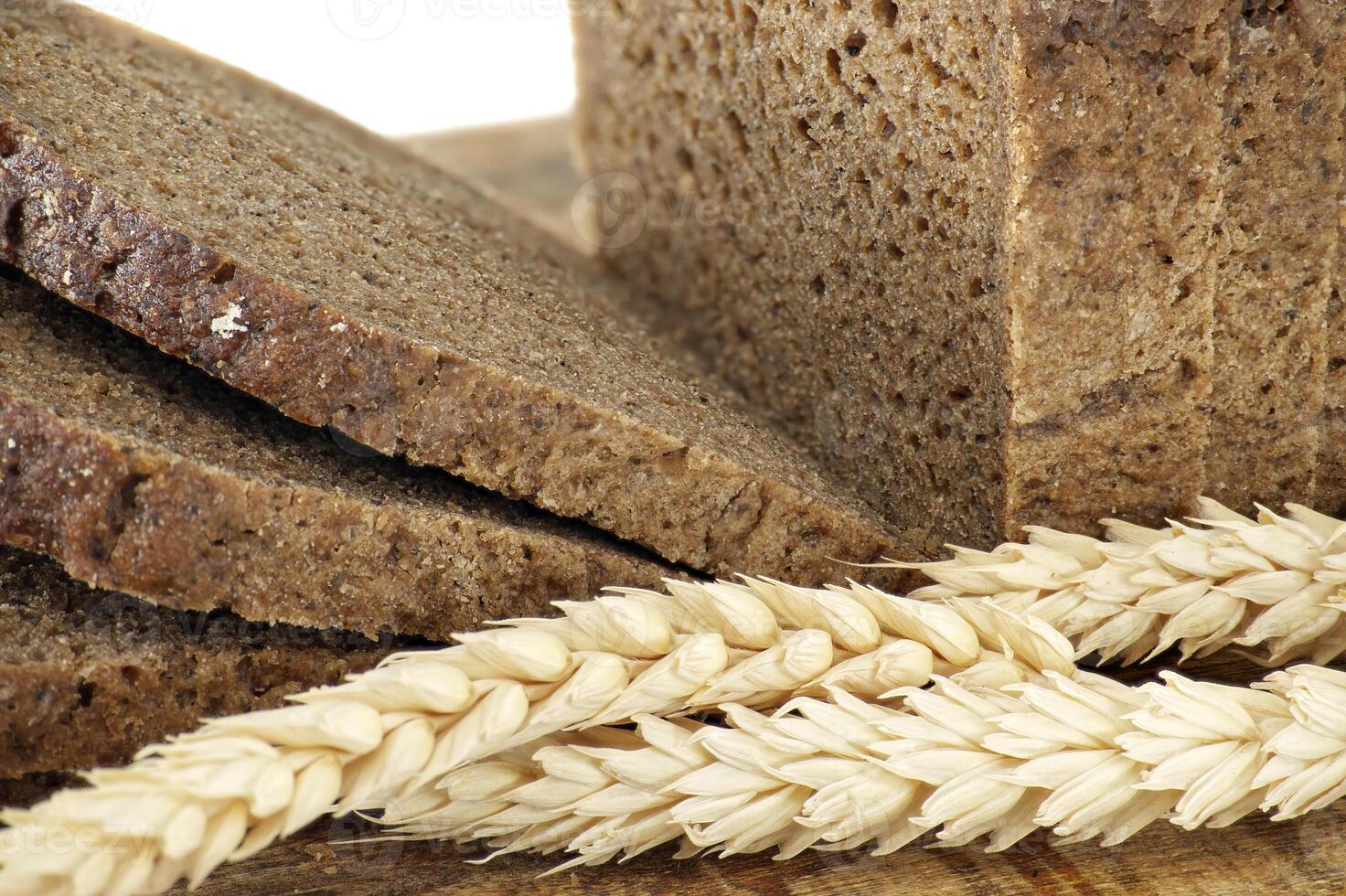 Close-Up of Sliced Whole-Grain Bread with Wheat Stalks on Wooden Surface photo