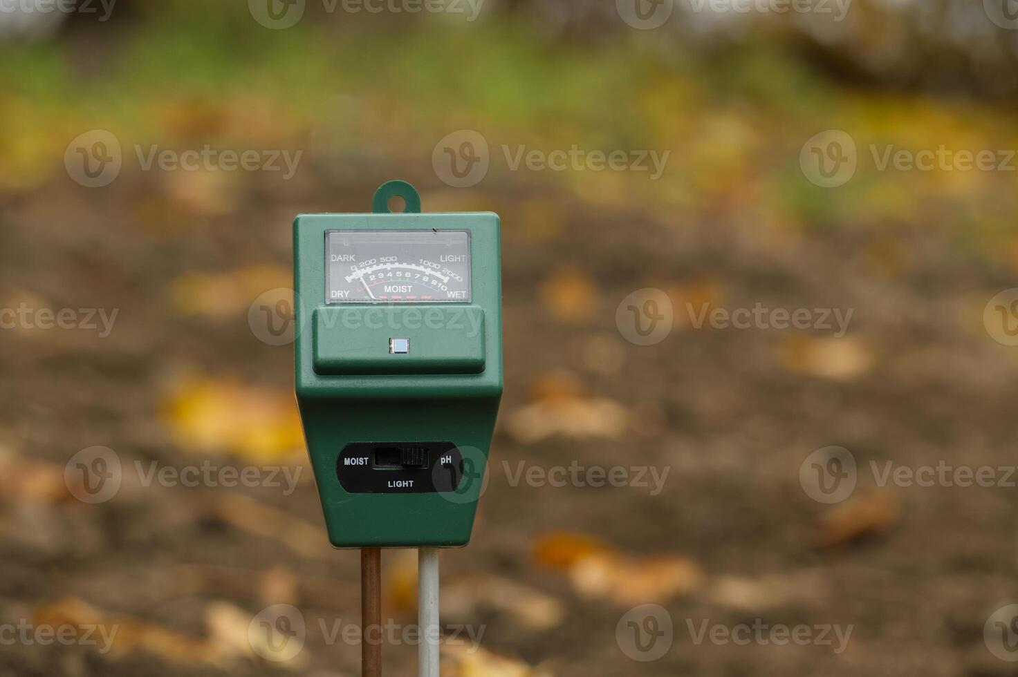 Close-up of soil moisture and pH meter in a garden setting to monitor plant care conditions photo