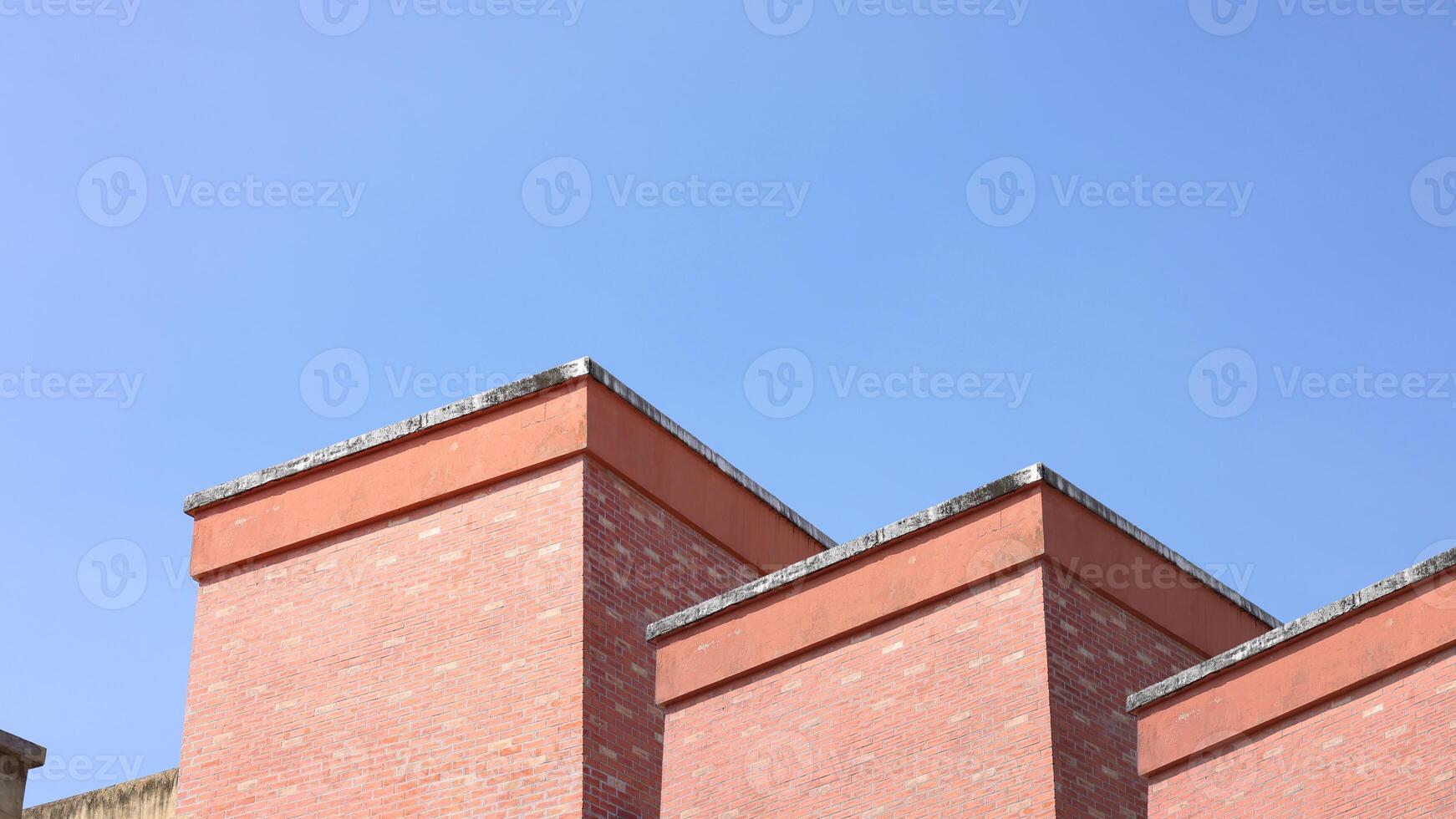 Red brick apartment building with sky, Shapes and simplicity of architecture, Fragment of roof of modern private dwelling house against of sky, Blue sky and Sunlight in background with copy space. photo