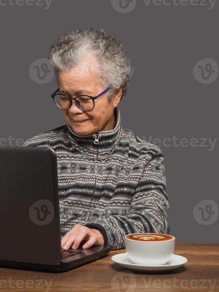 Senior woman uses a laptop to search for data from the internet while sitting at the table photo