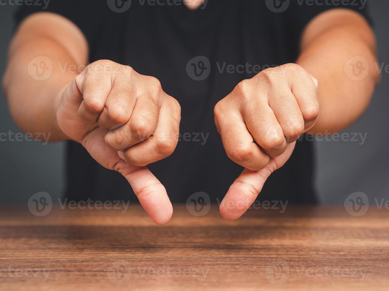 Close-up of young man's hands showing a thumbs down for dislike service photo