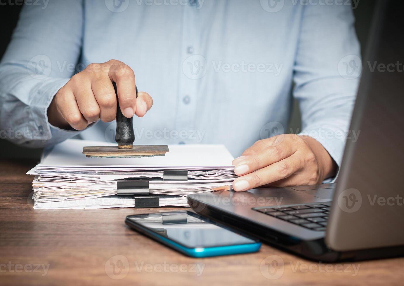 Businessman stamped for approved documents while sitting at the table in the office photo
