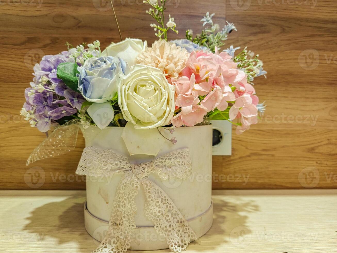 A white flower vase with a bow on it is filled with a colorful bouquet of flowers photo