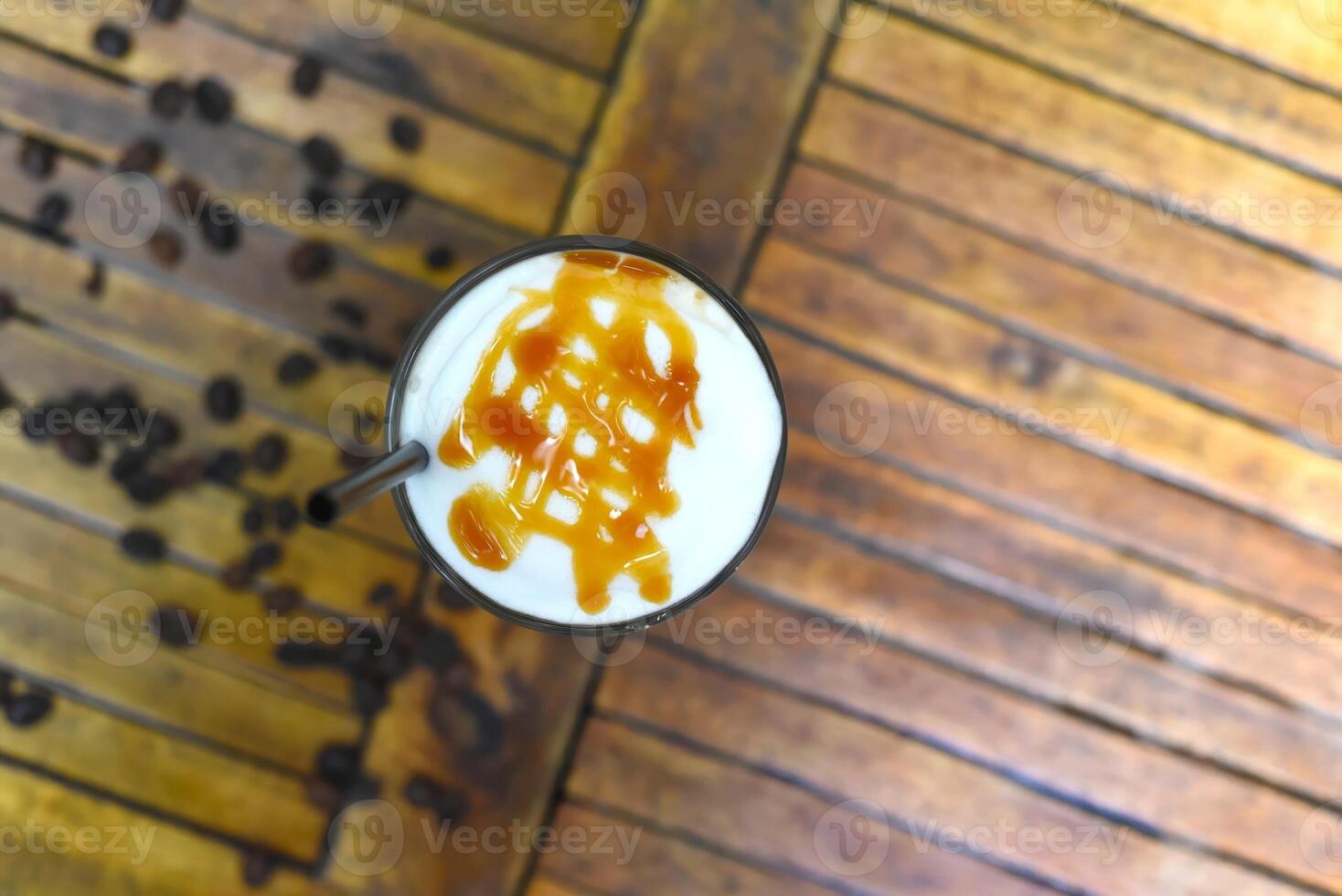 Ice caramel latte with coffee beans isolated on wooden table top view photo