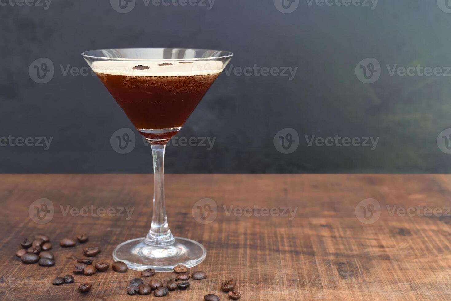 Glass of espresso martini with coffee beans on wooden table and black background photo
