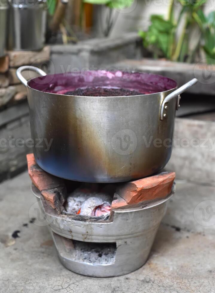 Boiling mulberry jam in metal saucepan on open fire photo