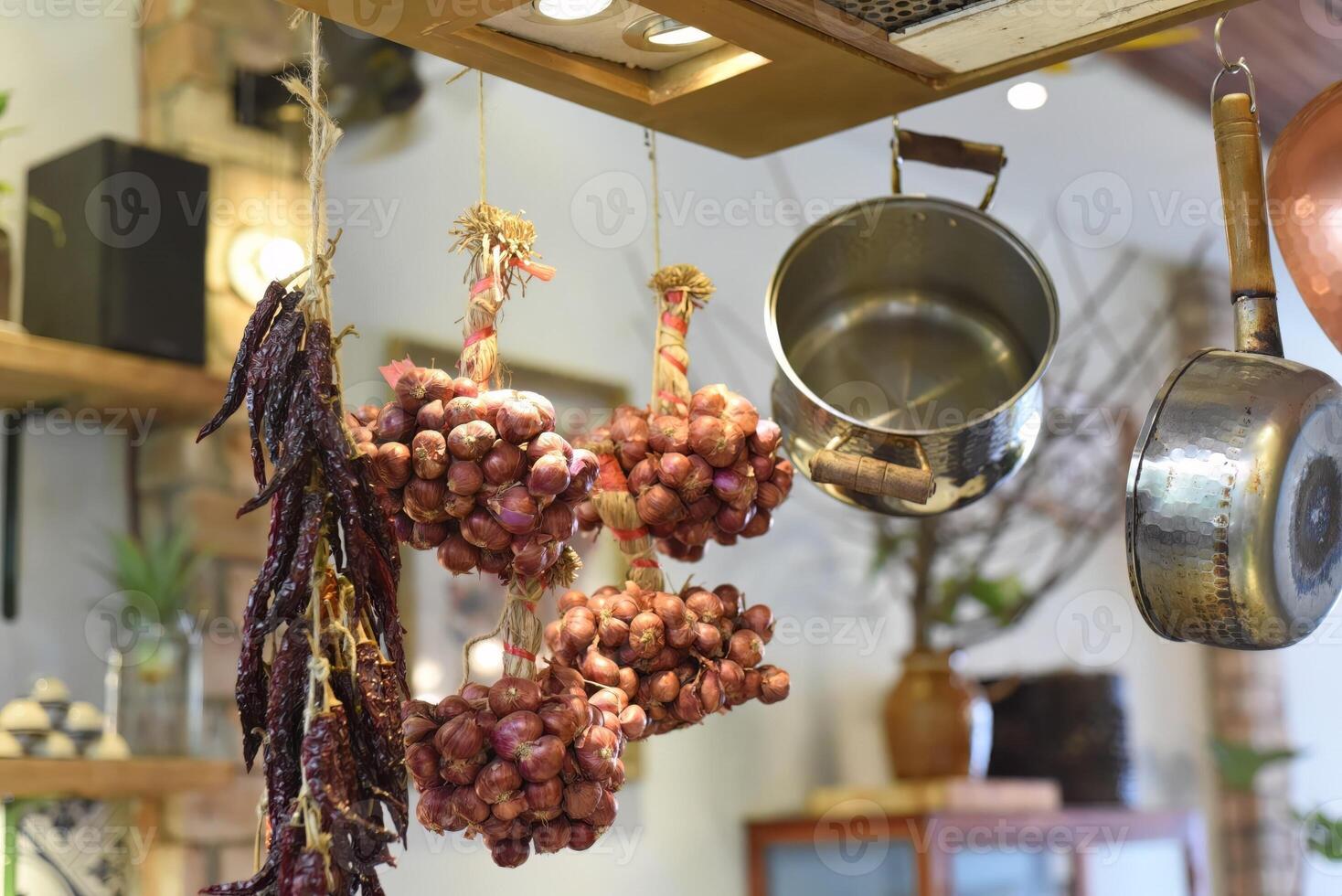 Dried garlic and red peppers hunging with saucepans in a kitchen photo