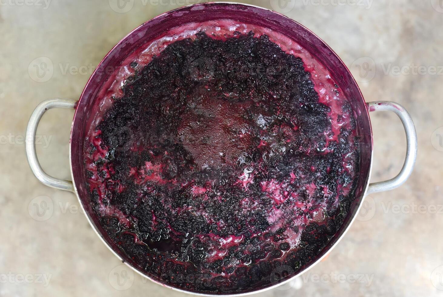 Boiling mulberry jam in metal saucepan on the open fire photo