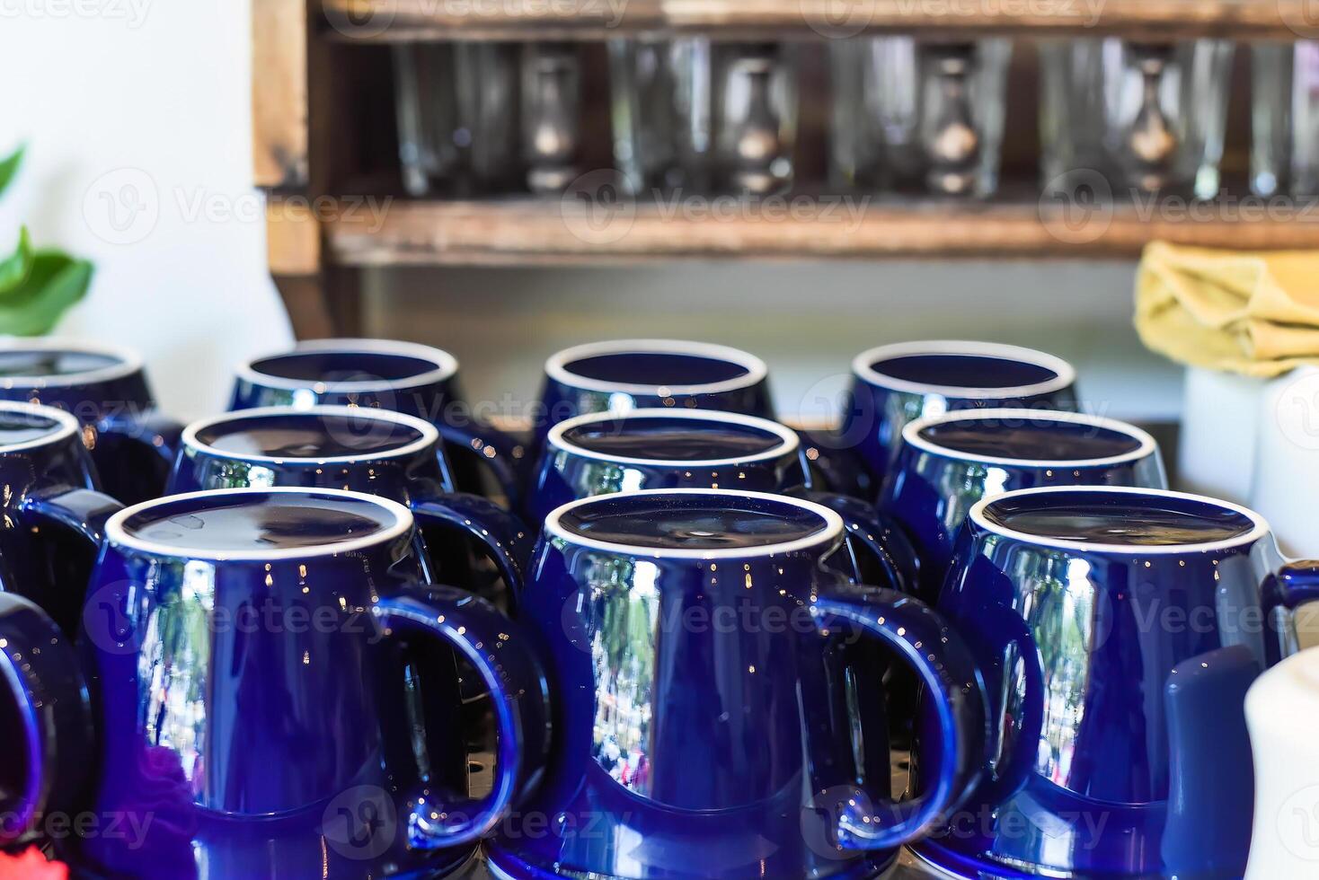 Many blue cups in a row on the woden shelf in the kitchen photo