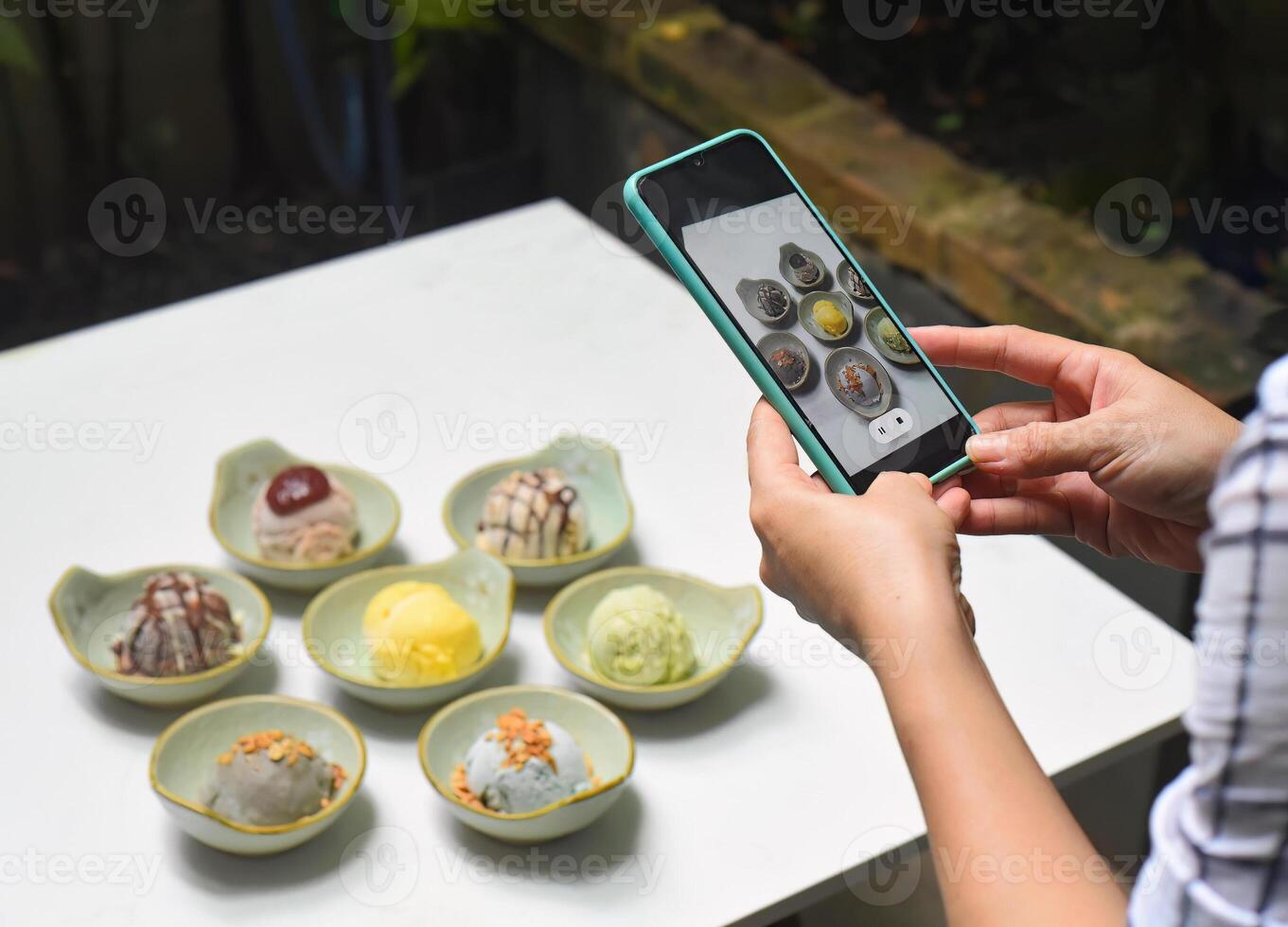 A woman taking picture of many ice cream on white table photo