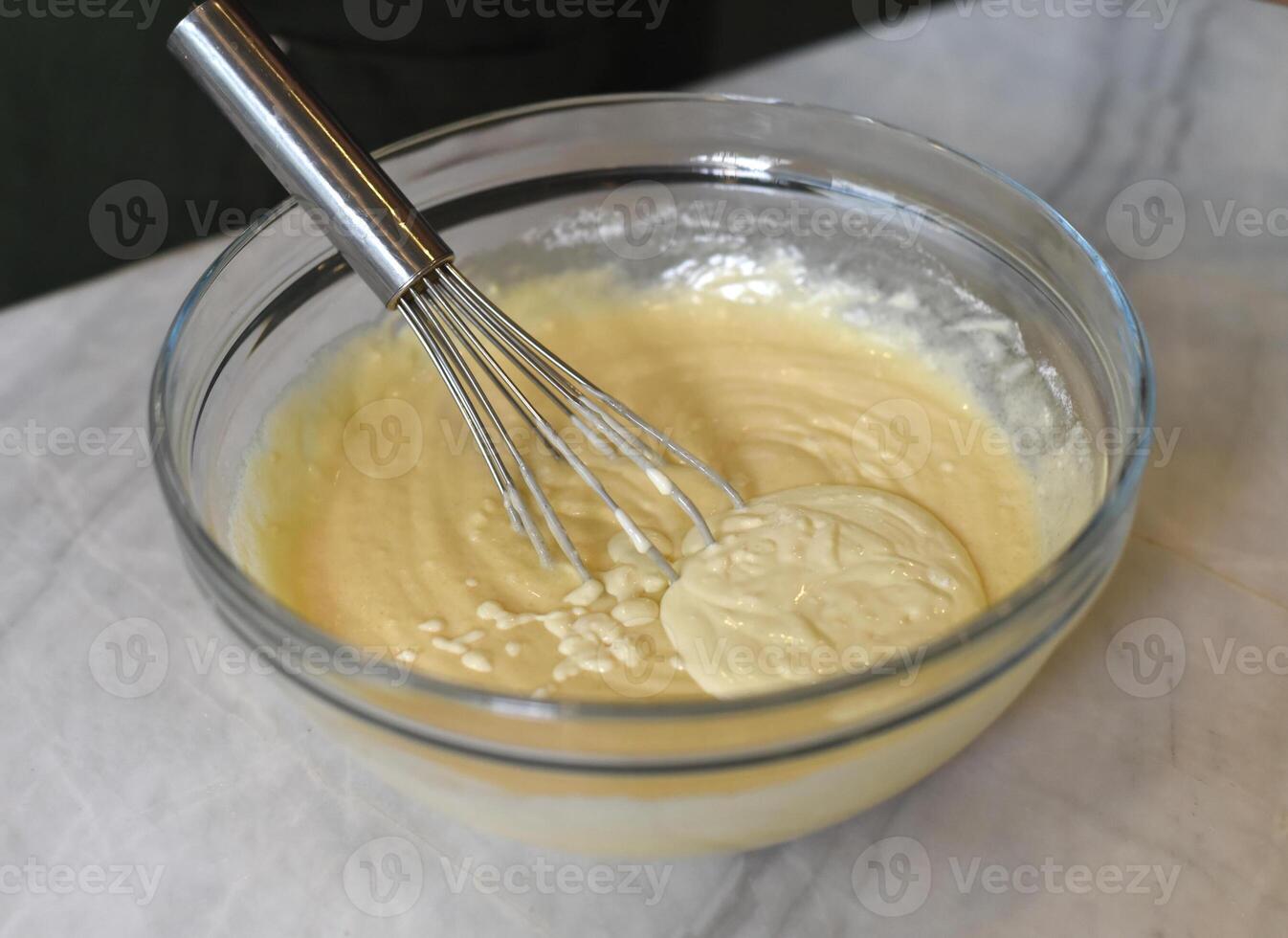 Egg beater in a glass bowl mixing dough photo
