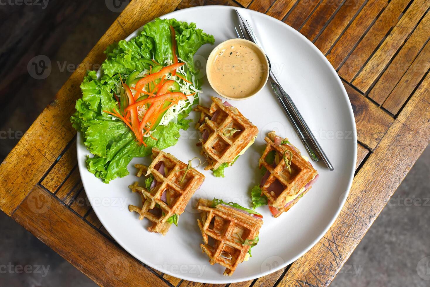Belgian waffles on a white plate with greens on wooden background photo